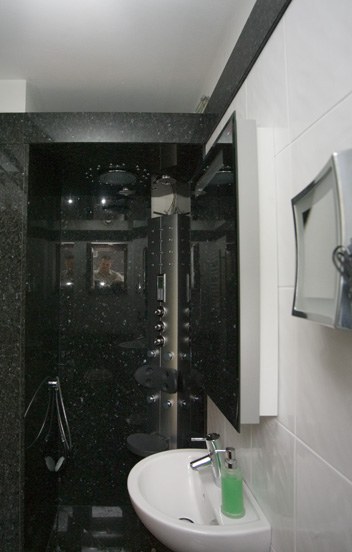 Gäste-WC mit Duschsauna, Wände und Boden aus dunklem Granit Emerald Pearl, weißes Waschbecken