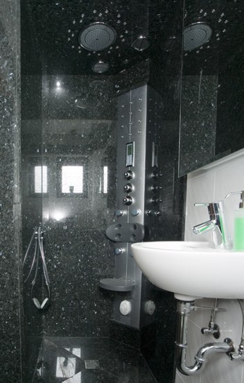 Dunkler Granit Emerald Pearl mit hellen Einschlüssen an Wand und Dusche eines Gäste-WCs