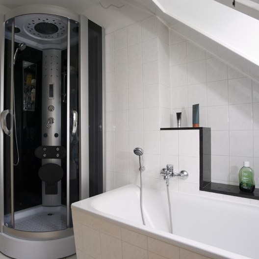 Bad unter der Dachschräge mit Eckbadewanne, Duschkabine und weißen Fliesen
